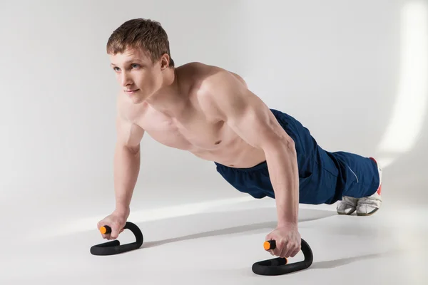 Musculoso deportista sin camisa haciendo flexiones en el estudio — Foto de Stock