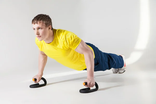 Musculoso deportista sin camisa haciendo flexiones en el estudio — Foto de Stock