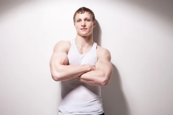 Portrait of a young sexy muscular man in underwear hands crosswise against white wall — Stock Photo, Image