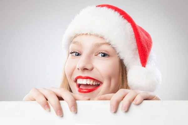 Mulher de Natal em santa chapéu segurando placa vazia — Fotografia de Stock