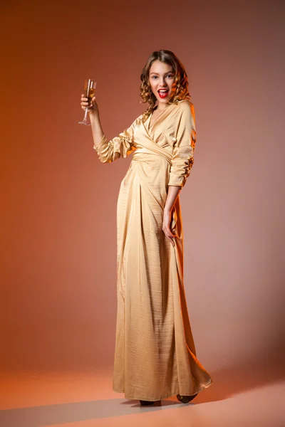 Mulher elegante em vestido dourado com vinho — Fotografia de Stock