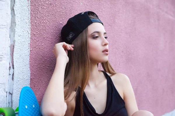 Chica joven con gorra y pantalones cortos sobre la pared — Foto de Stock