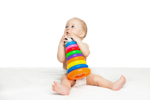 Милый ребенок, сидящий и играющий с цветной игрушкой — стоковое фото
