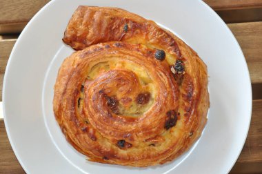 Beyaz tabakta kuru üzümlü çörek. 