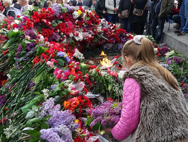 Kiev. Ukrayna. 9 Mayıs 2017 Zafer Anıtı 'nın ebedi ateşine bir kız çiçek bırakıyor.
