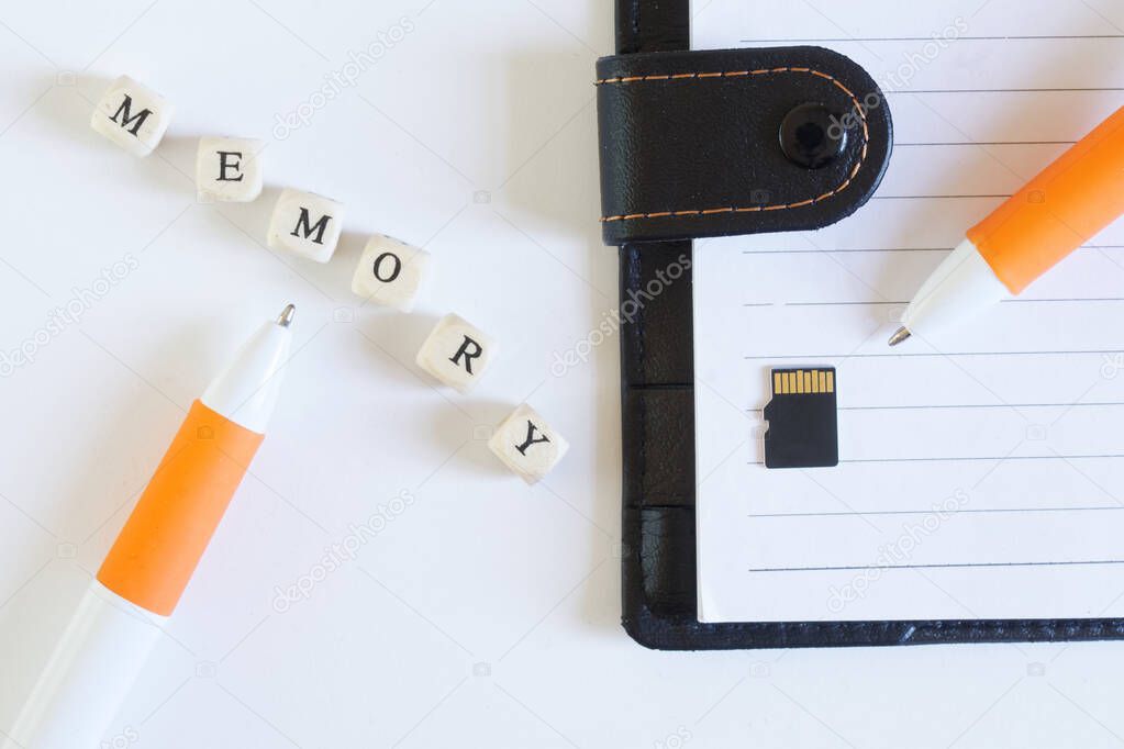 Micro-sd memory card next to an open notebook and a fountain pen. Comparison of modern memory storage and retro notebook. Modern digital technologies. Miniaturization. White background.