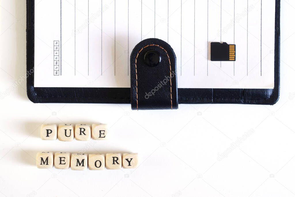 Pure memory lettering next to an open blank notebook and a blank micro SD memory card. An allegory of empty memory and a device for gadgets. Free space for an inscription.