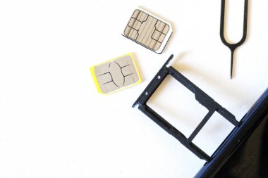 İki minyatür SIM kart ve beyaz arka planda fırlatıcının yanında çıkarılmış bir tepsi olan bir akıllı telefon. Akıllı telefon numarasını değiştiriyorum. Yakın plan. Bir yazı için boş alan. 