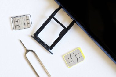 İki tane minyatür nano SIM kart ve iki boş yuva için silinmiş bir akıllı telefon beyaz arka planda fırlatıcının yanında duruyor. Akıllı telefon numarasını değiştiriyorum. Makro