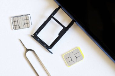 Two miniature nano SIM cards, and a smartphone with an removed tray for two empty slots lie next to the ejector on a white background. Replacing the smartphone number. Macro clipart