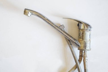 Beyaz arka planda eski bir kireçtaşı kaplı su musluğu var. Tesisat ekipmanlarının sökülmesi. Yakın plan..