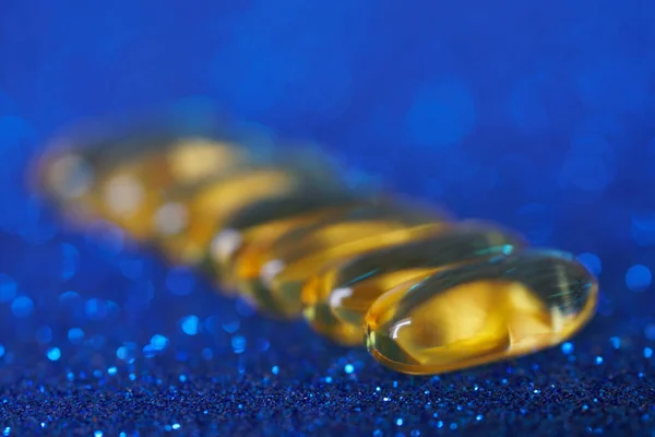 Cápsulas Aceite Pescado Color Dorado Encuentran Una Superficie Azul Brillante — Foto de Stock