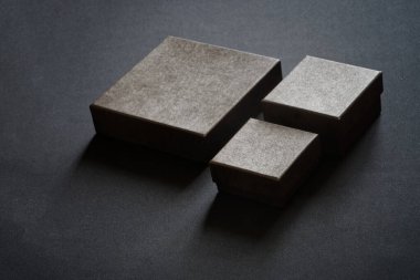 Etiketsiz üç kara kutu siyah arka planda duruyor. İndirim bekleyen gizli mallar ve Kara Cuma. Yakın plan.