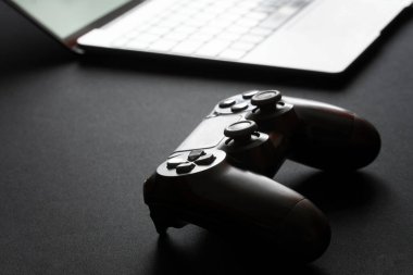 Video oyunları için joystick açık bir dizüstü bilgisayar ya da ultrabook 'un yanında bulunur. Arka ışıklandırma ve siluet. Profesyonel oyun konsepti. Yakın plan.