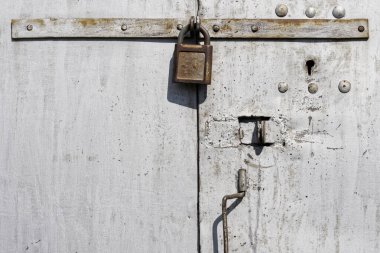 Uzun ayraçlara monte edilmiş bir asma kilit metal garajda ya da depo kapılarında asılı. Eski şeylerin depolanması ve korunması. Gün ışığı