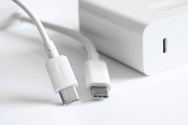 Kablolu iki beyaz usb tip-c konnektörü beyaz bir güç kaynağı ve hızlı şarj cihazının yanında hafif arka planda yatar. Modern teknoloji ve veri iletimi kavramı. Makro. Seçici Odaklanma