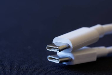 İki beyaz usb tip-c konnektörü koyu mavi arka planda yatar. Yakın plan. Makro. Bokeh. Bir yazı için boş yer. Seçici odak