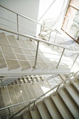 Modern çok katlı bir binanın içinde metal parmaklıklı beş güneşli merdiven. Mimarlık elementi