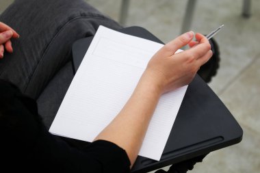 A girl is preparing to fill out a blank form, write an essay or dictation, sitting on a school chair with a writing stand. View from above. No face clipart