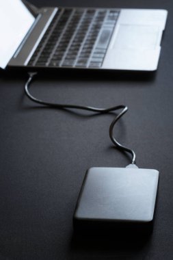 Dış periferik aygıt - 2.5 sabit disk dizüstü bilgisayara ya da ultrabook 'a bağlı. Veri transferi. Karanlık masa. Yakın plan.