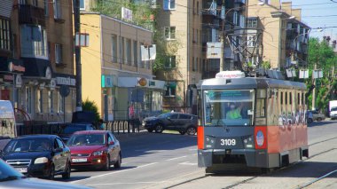 Şehir caddesinde siyah ve kırmızı renkli modern tek taşıma tramvayı. Alışılmadık ayarlanmış vücut. Paved tramvay rayları. 24 Mayıs 2021, Rusya, Magnitogorsk. İade