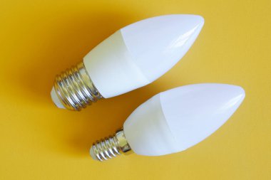 Sarı arka planda LED ampuller. Küçük - E14 ve büyük - E27 LED lamba tabanı karşılaştırması. Yakın plan.