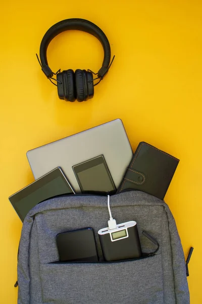 現代的なガジェットのセット 外部バッテリー ラップトップ タブレット スマートフォンはファッショナブルなテキスタイルバックパックにあります 黄色の背景 旅行や旅行中にガジェットを充電する概念 — ストック写真