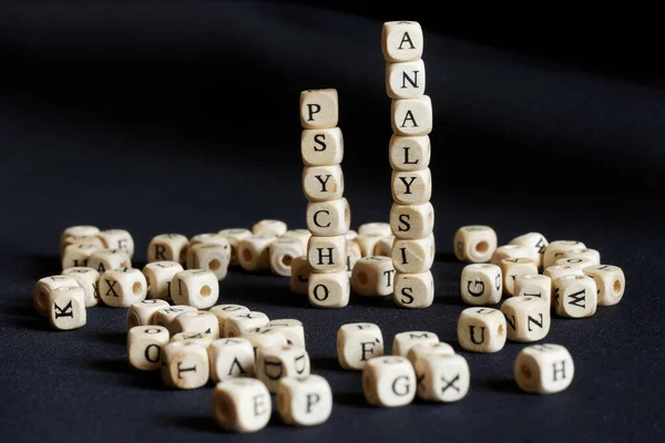 Turrets made of cubes with the word psychoanalysis. Dark background. The concept of human mental problems and the use of psychoanalysts. Macro. Close-up