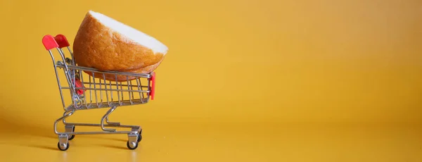 Een Stuk Brood Ligt Een Supermarkt Trolley Gele Achtergrond Het — Stockfoto