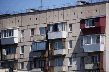 Çok katlı bir binanın duvarına rastgele yerleştirilmiş farklı dizayn ve camlardan oluşan bir balkon çeşitliliği. 17 Haziran 2021, Rusya, Magnitogorsk. Kentsel