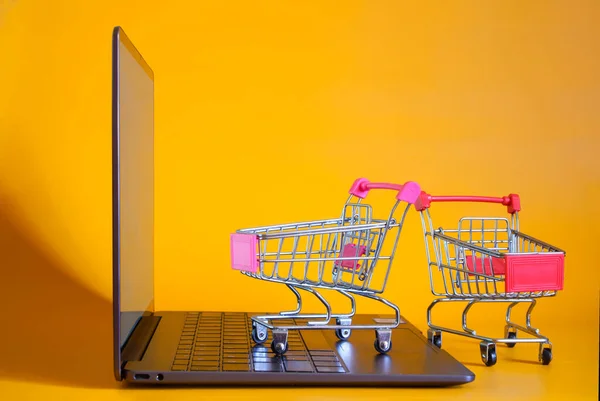 Fashionable Slim Laptop Two Carts Supermarket Yellow Background Concept Shopping — Stok fotoğraf