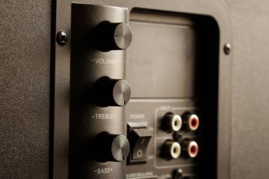 Güçlü subwoofer 'ın arkasında ses, titreşim ve bas kontrolleri var. Üst düzey ses ekipmanlarında ses ve ses kontrollerinin dikey düzenlenmesi. İşitsel kişilik konsepti. Seçici odaklanma. Yakın plan.