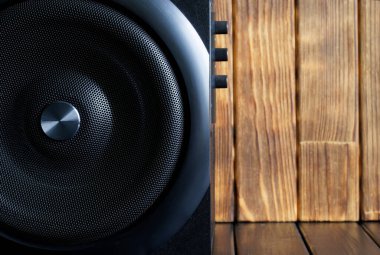 Metal ızgara, ses ve ton kontrollü ahşap bir çantanın içindeki yüksek sesli subwoofer doğal kalasların arka planına karşı duruyor. İşitsel kişilik konsepti. İskandinav tarzı. Yakın plan.