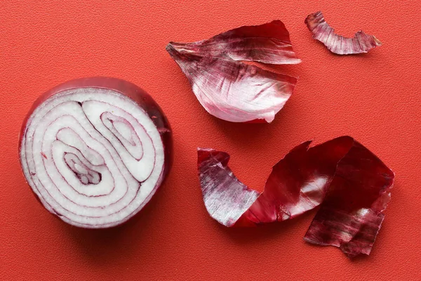 Halva Röd Lök Ligger Röd Bakgrund Bredvid Ett Skalat Lökskal — Stockfoto