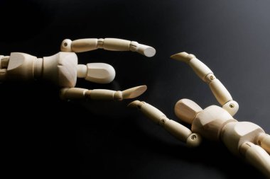 İki ahşap manken, karanlık bir arka plana karşı ellerini uzatıyorlar. Yalnızlık, cinsiyet kimliği ve eş bulma kavramı. Yakın plan.