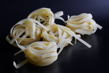  Mutfak masasının karanlık yüzeyinde bir sürü kırmızı buğday fettucine makarna var. Gün ışığı. Yakın plan.