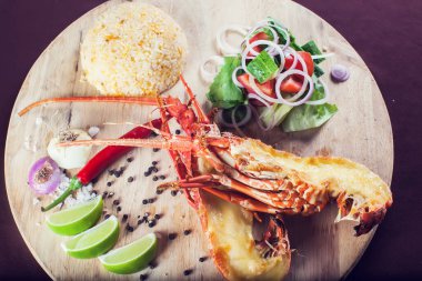 Bir sürü sebzeyle süslenmiş ve kızartılmış lüks bir ıstakoz tabağı.