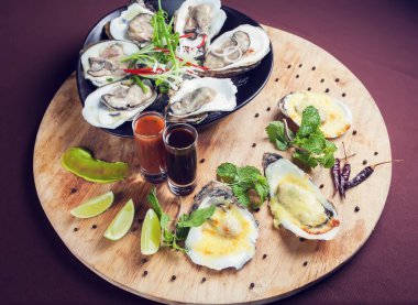 Buzlu deniz mahsullerinde acilmis istiridye taze ve ahşap tepside sosla servis ediliyor.