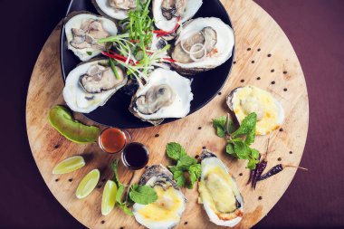 Buzlu deniz mahsullerinde acilmis istiridye taze ve ahşap tepside sosla servis ediliyor.