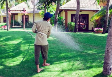 Adam bahçedeki çimlere su döktü.