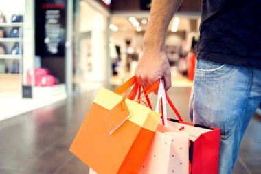 Alışveriş merkezinden alışveriş yapan, alışveriş çantalı yakışıklı bir adam görüntüsü.