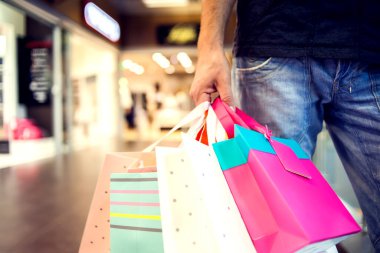 Alışveriş merkezinden alışveriş yapan, alışveriş çantalı yakışıklı bir adam görüntüsü.