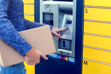 Paketi depolamak için otomatik self servis terminal makinesi veya dolap kullanan kadın istemci,