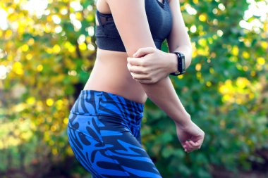 Genç bir kadın parkta spor yaparken dirseğinde ağrı hissediyor. Spor, tıp ve insan konsepti