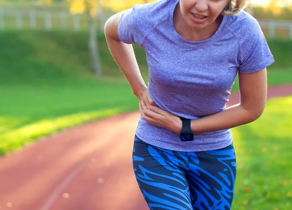 Yan dikiş - koşudan sonra kadın atlet yan krampları. Koşu yaptıktan sonra karın ağrısı çeken bir kadın. Kadın sporcu. Spor, sağlık ve insan kavramı