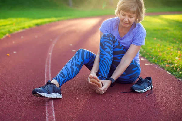 Spor, spor, egzersiz ve sağlıklı yaşam tarzı konsepti. Stadyumda bacağı yaralı genç bir kadın.