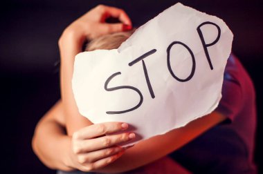Kadın, siyah arka planda kendisine yardım etmesi için elinde mesajla kâğıt tutuyor. İnsanlar, aile içi şiddet, suç kavramı