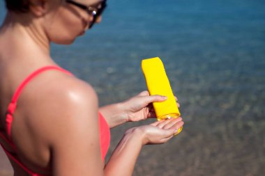 Kadın, cildine güneş koruyucu krem sürüyor. Halk, sağlık ve yaz konsepti