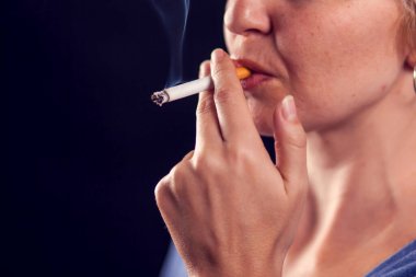 Kadın siyah arka planda sigara içiyor. Tütün bağımlılığı konsepti