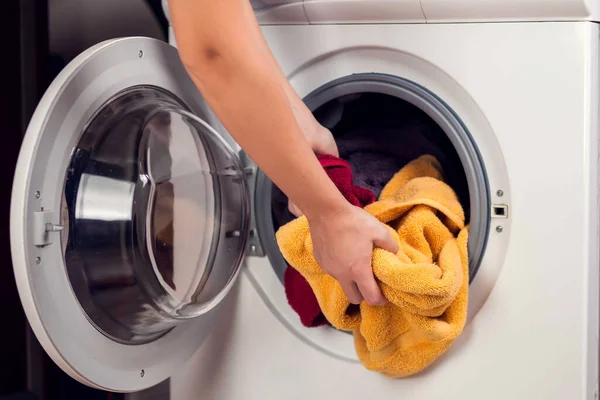 Loading clothes in washing machine. Housework, laundry concept